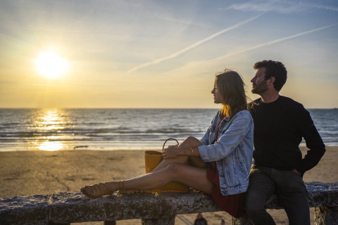 Couple watching the sunset on the beach at Camping Saint Pabu Plage - Glamping Bretagne in France.