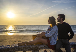 Pareja mirando la puesta de sol en la playa de Camping Saint Pabu Plage - Glamping Bretagne en Francia.