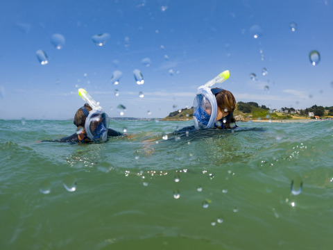 Two people snorkeling in the sea near Camping Saint Pabu Plage - Glamping Bretagne on a bright sunny day.
