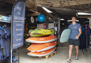 Mann mit Surfbrett in der Materialausgabe bei Camping Saint Pabu Plage - Glamping Bretagne.