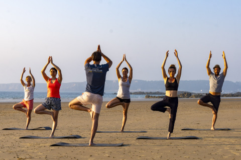 Groupe faisant du yoga sur la plage au Camping Saint Pabu Plage - Glamping Bretagne, ambiance détendue.