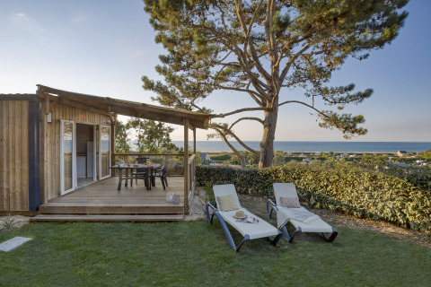 Alojamiento glamping con terraza de madera, tumbonas y vistas al mar en Camping Saint Pabu Plage - Glamping Bretagne.