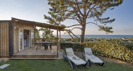 Hébergement glamping avec terrasse en bois, transats et vue sur mer au Camping Saint Pabu Plage - Glamping Bretagne.