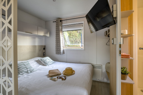 Indretning af et lyst glampingværelse på Camping Saint Pabu Plage med dobbeltseng, TV og vindue.