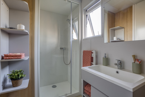 Modernes Badezimmer mit Dusche, Waschbecken und Regalen im Camping Saint Pabu Plage - Glamping Bretagne.