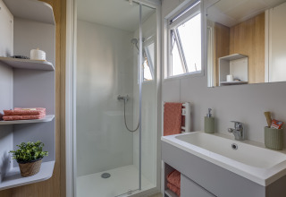 Baño moderno con ducha, lavabo y estanterías en Camping Saint Pabu Plage - Glamping Bretagne.
