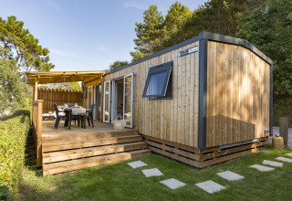 Moderne glampingaccommodatie met houten terras en buitentafel bij Camping Saint Pabu Plage, Glamping Bretagne.
