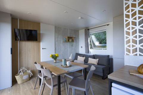 Interior moderno de alojamiento glamping en Camping Saint Pabu Plage en Bretaña con comedor y sofá.