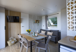 Modern glamping accommodation at Camping Saint Pabu Plage in Brittany, featuring dining area and cozy sofa.