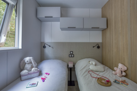 Twee eenpersoonsbedden in een glampingkamer op Camping Saint Pabu Plage met knuffels en modern interieur.