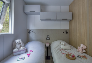 Dos camas en habitación glamping del Camping Saint Pabu Plage, con peluches y decoración moderna en Bretaña.