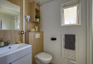 Baño moderno en alojamiento glamping Camping Saint Pabu Plage con toques de madera y ventana iluminada.