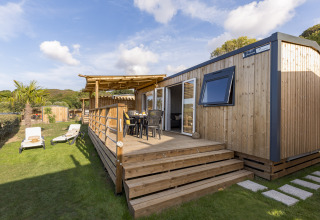 Hébergement glamping moderne avec terrasse en bois et chaises longues au Camping Saint Pabu Plage en Bretagne.