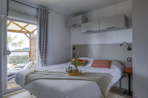 Dormitorio de glamping moderno en Camping Saint Pabu Plage en Bretaña con cama doble y terraza exterior.