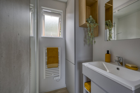 Baño moderno en Camping Saint Pabu Plage - Glamping Bretagne, decoración luminosa y toalla amarilla.