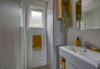 Bagno moderno al Camping Saint Pabu Plage - Glamping Bretagne, arredo chiaro e asciugamano giallo.