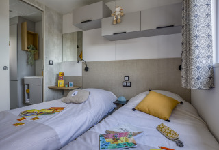 Modern glamping accommodation with twin beds, cozy decor and sunlight at Camping Saint Pabu Plage, Brittany.