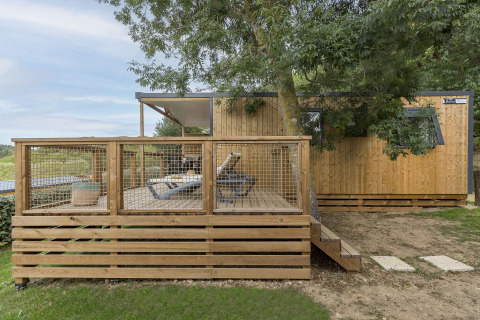 Glamping accommodation at Camping Saint Pabu Plage featuring a wooden terrace and loungers in Brittany, France.