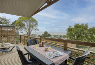 Houten terras met uitzicht op zee bij Camping Saint Pabu Plage - Glamping Bretagne, buitentafel gedekt voor ontbijt.