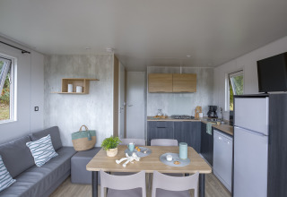 Moderne glampingbolig på Camping Saint Pabu Plage i Bretagne med køkken, spisebord og sofa.