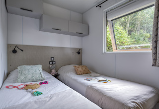 Innenaufnahme eines Zimmers mit zwei Einzelbetten und großem Fenster im Camping Saint Pabu Plage Glamping.