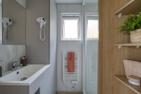 Baño moderno en Camping Saint Pabu Plage - Glamping Bretagne con lavabo, espejo, secador y toalla decorativa.