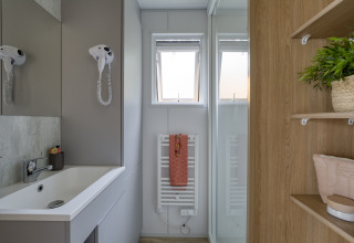 Bagno moderno al Camping Saint Pabu Plage - Glamping Bretagne con lavabo, specchio, asciugacapelli e asciugamano.