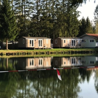 Alloggi glamping sul lago presso Camping Ammertal - Stacaravans Beieren, circondati da alberi e natura.