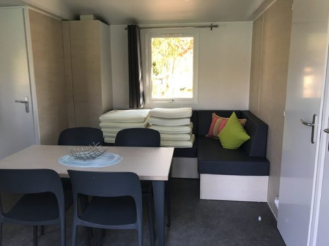 Interno di una sistemazione glamping al Camping Ammertal con tavolo, sedie nere e divano ad angolo.