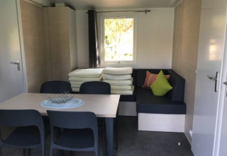 Interieur van glamping accommodatie op Camping Ammertal met tafel, zwarte stoelen en hoekbank.