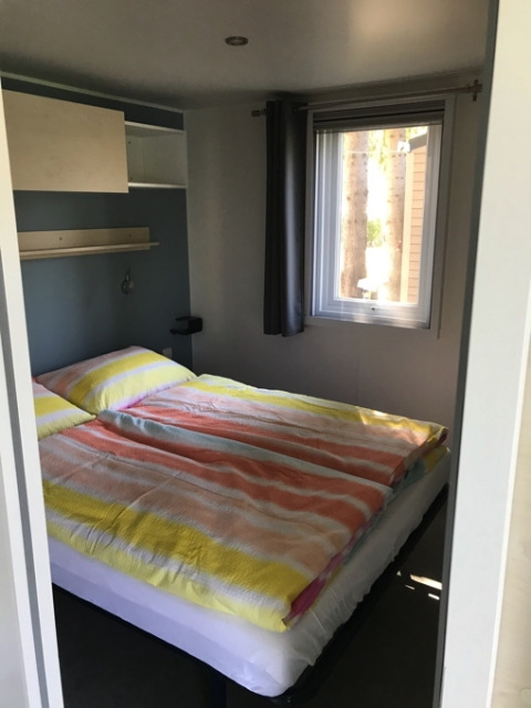 Slaapkamer in een glampingaccommodatie bij Camping Ammertal - Stacaravans Beieren met kleurrig beddengoed.