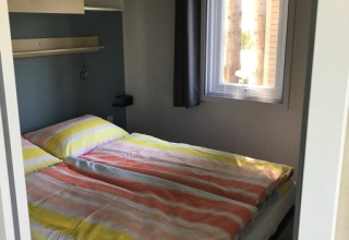 Bedroom inside glamping accommodation at Camping Ammertal - Stacaravans Beieren with colorful bedding.