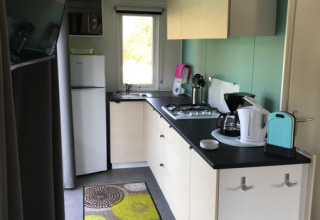 Cucina glamping moderna al Camping Ammertal - Stacaravans Beieren con elettrodomestici e tappeto colorato.