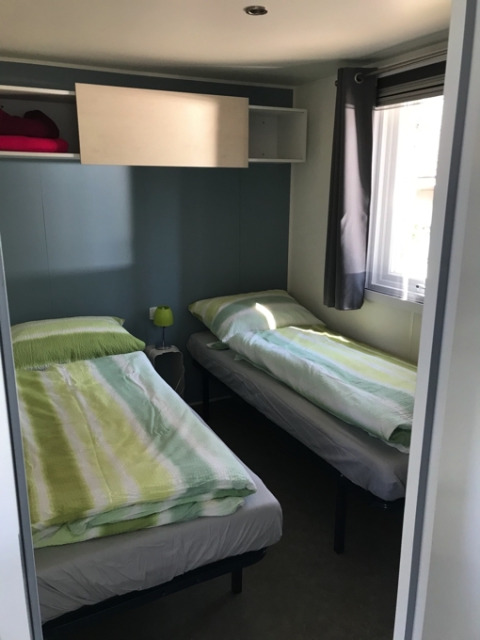 Dos camas individuales en una habitación glamping luminosa de Camping Ammertal - Stacaravans Beieren con ventana.