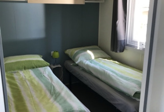 Deux lits simples dans une chambre glamping lumineuse au Camping Ammertal - Stacaravans Beieren, avec fenêtre.