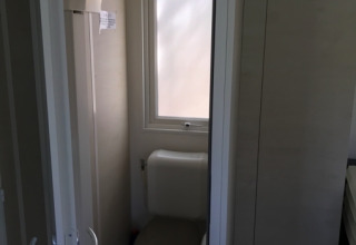 Baño con inodoro y ventana en un alojamiento glamping en Camping Ammertal - Stacaravans Beieren.