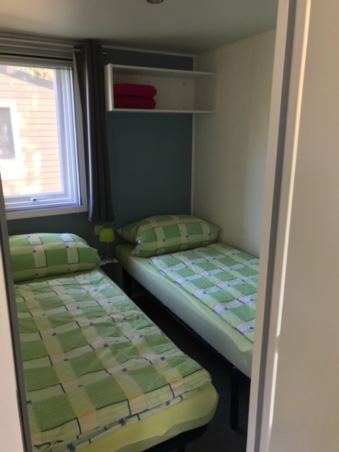 Zwei Einzelbetten mit grüner Bettwäsche in einem Zimmer im Camping Ammertal - Stacaravans Beieren.