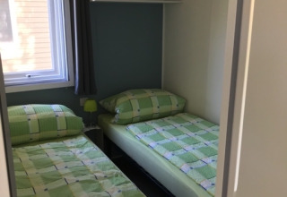 Deux lits simples avec une literie verte dans une chambre au Camping Ammertal - Stacaravans Beieren.