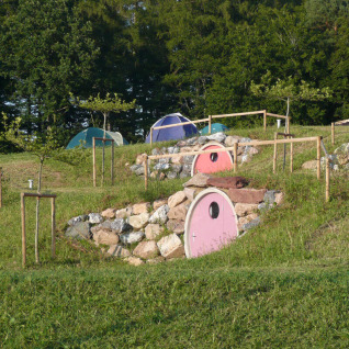Glamping indkvartering med små hobbithuse i grønne bakker ved Camping & Vakantiepark Orsingen, Tyskland.