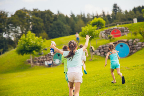 Niños corren y juegan en un césped frente a cabañas redondas y coloridas en Camping & Vakantiepark Orsingen Glamping Baden-Württemberg.
