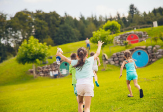 Des enfants courent et jouent devant des cabanes rondes colorées au Camping & Vakantiepark Orsingen Glamping Baden-Württemberg.