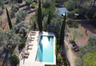 Vista aerea del glamping Refugio Marnes con piscina, lettini e paesaggio naturale in Spagna.