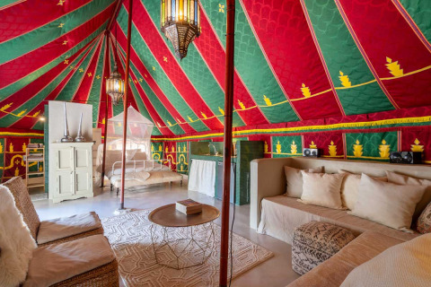 Interieur van een glamping tent met kleurrijk plafond, zithoek en bed bij Refugio Marnes agriturismo Spanje.