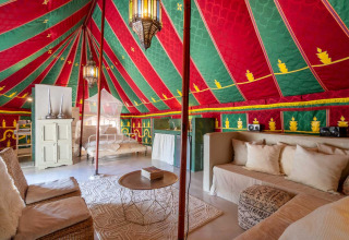 Interno di una tenda glamping con soffitto colorato, area relax e letto a Refugio Marnes agriturismo Spagna.