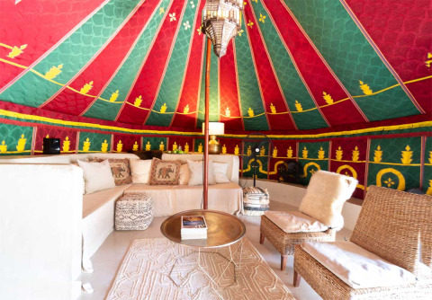 Intérieur coloré d’une tente glamping à Refugio Marnes en Espagne, avec salon confortable et déco orientale.