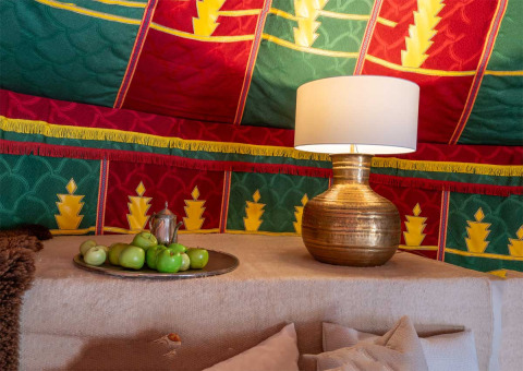 Arredo colorato nella tenda glamping Refugio Marnes con lampada, frutta verde e pareti decorate visibili.