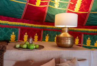 Arredo colorato nella tenda glamping Refugio Marnes con lampada, frutta verde e pareti decorate visibili.