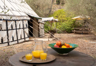 Glamping at Refugio Marnes - Agriturismo Spanje featuring a tent, outdoor table, fruit bowl and orange juice.