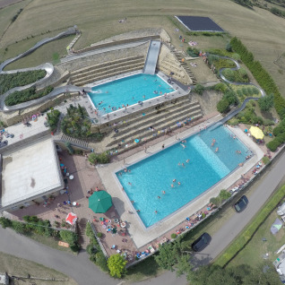 Vue aérienne du Camping Altschmiede - Lodges Rhénanie-Palatinat avec piscines, toboggan et emplacements.