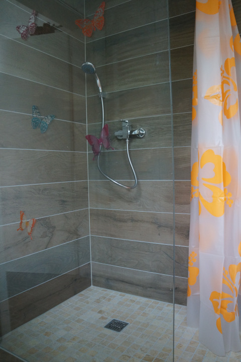 Douche met vlinderdecoratie en oranje gordijn in een glamping lodge van Camping Altschmiede, Rijnland-Palts.